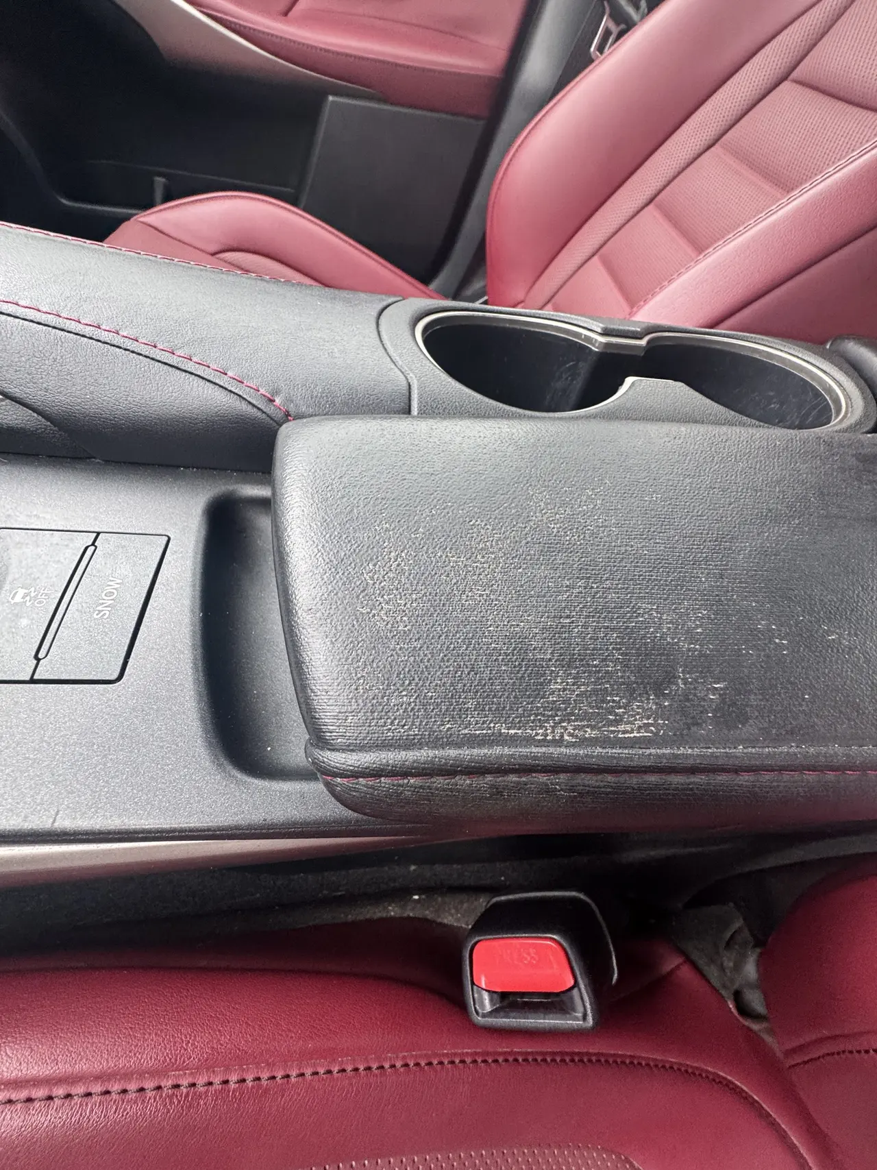 Worn leather centre console armrest before repair